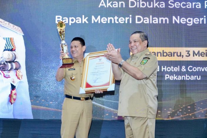 Pj Gubernur Riau SF Hariyanto menyerahkan penghargaan dan tropi kepada Pj Bupati Kampar Hambali